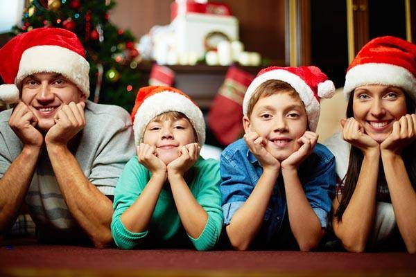 A happy family smiling and wearing Christmas hats