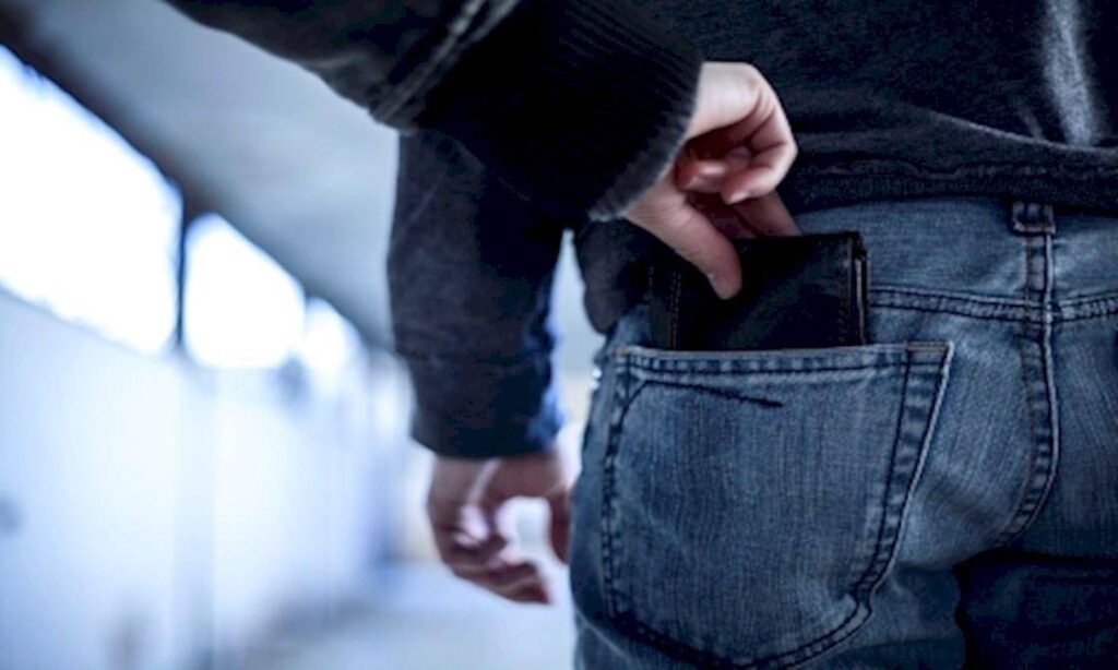 Someone pick pocketing a man's wallet from his jeans
